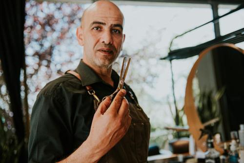 a man holding a comb in front of a mirror at Wabi Hotel - Beauty & Dental Center in Sopron