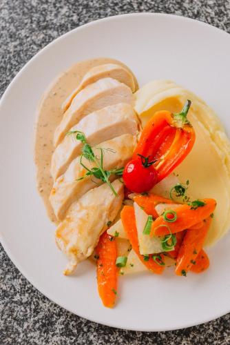 a plate of food with chicken and vegetables on a table at Wabi Hotel - Beauty & Dental Center in Sopron