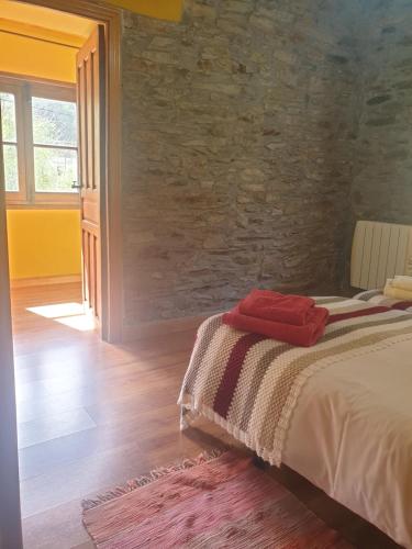 sypialnia z łóżkiem i kamienną ścianą w obiekcie Valles del Narcea, Apartamentos Rurales w mieście Cangas del Narcea