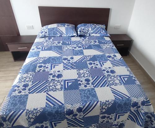 Una cama con un edredón azul y blanco. en HOSTAL PARIS, en Manta