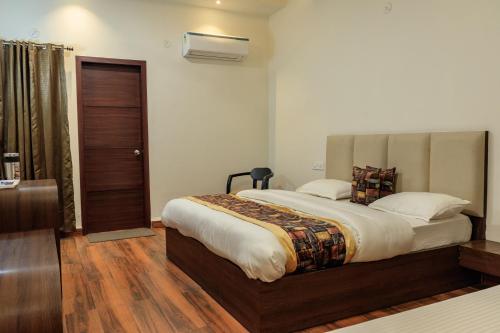 ein Schlafzimmer mit einem großen Bett und Holzboden in der Unterkunft De Manora Homes - Unpretentious hotel with a garden , posh area Ranjit Avenue in Amritsar