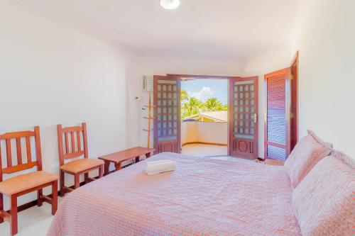 a bedroom with a bed and two chairs and a window at GB09 Ótima Casa 6 Quartos a 50m da Praia in Guarajuba
