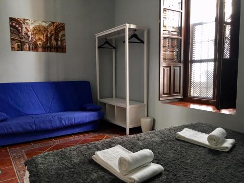 ein Wohnzimmer mit einem blauen Sofa und zwei weißen Handtüchern in der Unterkunft Patio de la Plateria in Córdoba