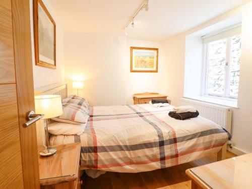 niewielka sypialnia z łóżkiem i oknem w obiekcie Harbour Suite w mieście Porthmadog