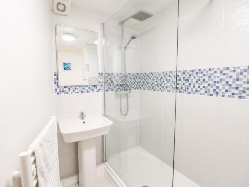 a white bathroom with a shower and a sink at Harbour Suite in Porthmadog