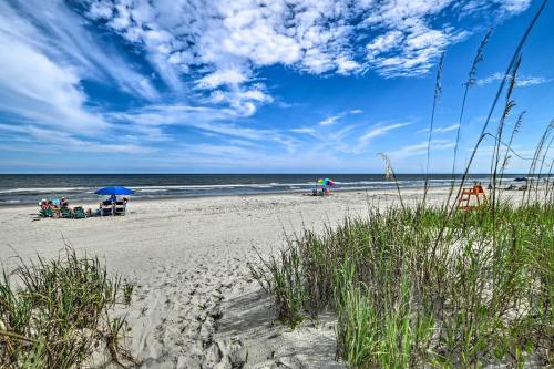a group of people sitting under umbrellas on a beach at Myrtle Beach Condo with On-Site Pool and Beach Access in Myrtle Beach