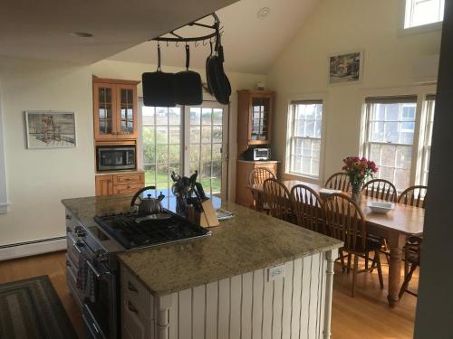 a kitchen with a stove and a table with chairs at Love Sand, Madaket on the Beach in Nantucket