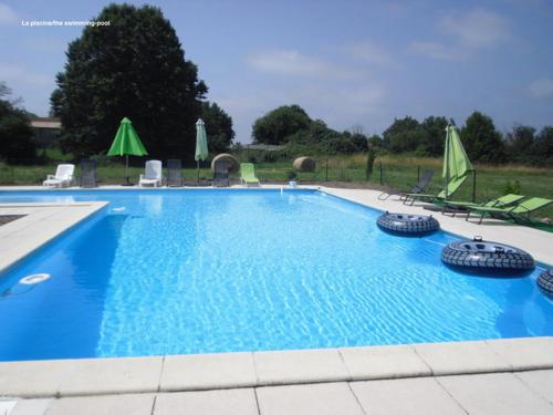 une grande piscine bleue avec chaises et parasols dans l'établissement La Galerie gîte climatisé 4 chambres 8 personnes 2 salles d'eau WIFI parking piscine chauffée animaux acceptés Gîte en pleine nature, à Lorignac