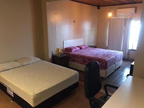 um quarto de hotel com duas camas e uma mesa e cadeiras em Casa LB com estacionamento privado em Boa Vista