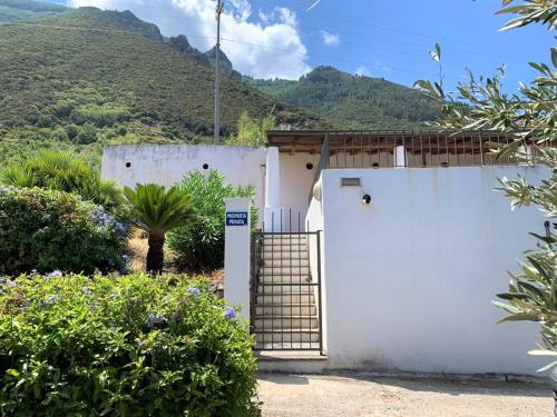 una casa blanca con una puerta y montañas al fondo en Casa Nina - Villetta indipendente con ampio terrazzo panoramico en Malfa