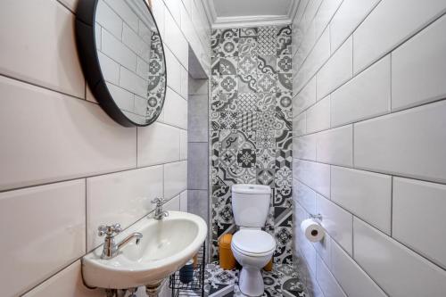 a bathroom with a sink and a toilet and a mirror at Hampton Collection - Trendy 2 Sleeper Apartment with Pool in Durban