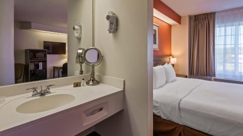 a bathroom with a sink and a bed in a hotel at Charlevoix Inn & Suites SureStay Collection by Best Western in Charlevoix
