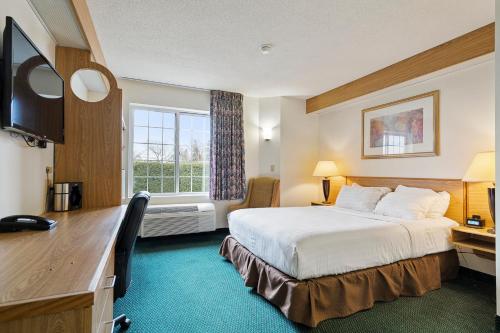 ein Hotelzimmer mit einem Bett und einem Schreibtisch in der Unterkunft Charlevoix Inn & Suites SureStay Collection by Best Western in Charlevoix