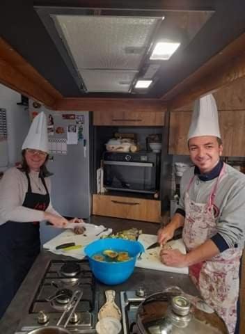 un uomo e una donna in una cucina che preparano il cibo di Appartment Carib in Castelbuono a Castelbuono