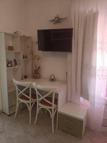Camera con scrivania, 2 sedie e TV. di Appartment Carib in Castelbuono a Castelbuono