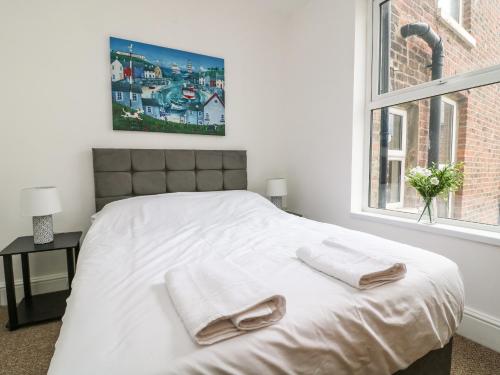 a white bedroom with a bed with two towels on it at The Dukes Apartments, Flat 3 in Scarborough