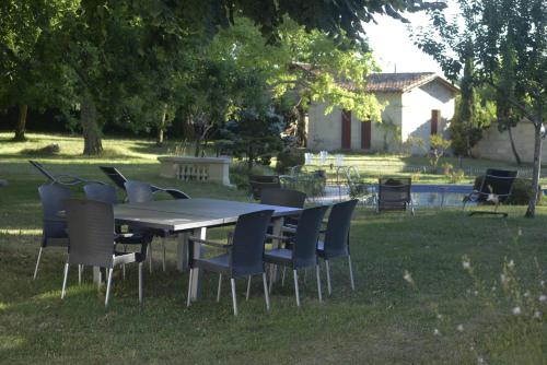 una mesa y sillas en el césped en un patio en Château Rosemont - Grande maison familiale campagne dans le Médoc avec piscine et tennis à 15 mn Bordeaux en Labarde