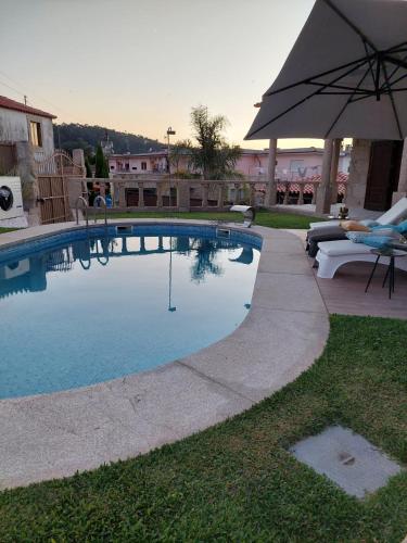 a swimming pool with an umbrella next to a yard at Deluxe Villa Home, Peace & Spa in Vila do Conde