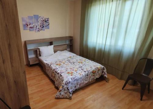 een slaapkamer met een bed en een stoel erin bij Ваканция in Velingrad