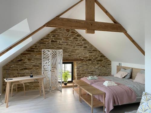 1 dormitorio con cama y pared de piedra en Chambres d'Hôtes Bella Laïta, en Keranquernat