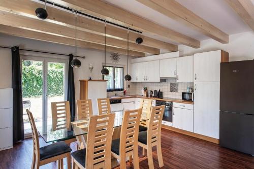 cocina con armarios blancos, mesa y sillas en Grande villa indépendante, en Evionnaz