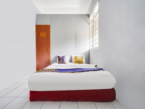a bedroom with a large bed in a white room at SPOT ON 91393 Budiluhur 10 Homestay in Bandung