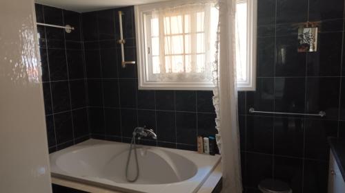 ein Bad mit einer Badewanne und einem Fenster in der Unterkunft Greenfields Country Club in Limassol