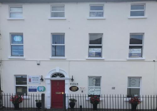 un edificio blanco con puerta roja y ventanas en Serenity en Longford