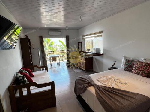 a bedroom with a bed and a table and a window at Residencial Solariun Ilhabela in Ilhabela