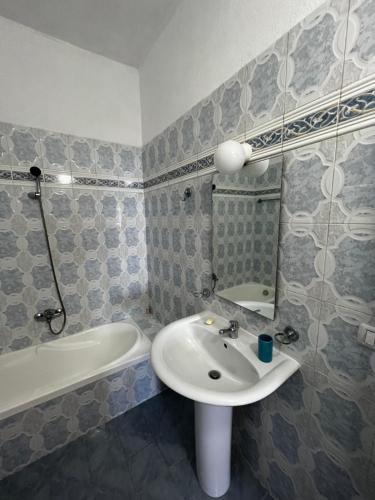a bathroom with a sink and a mirror and a tub at Traditional old house in Dhërmi