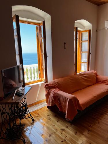 a living room with a couch and a large window at Traditional old house in Dhërmi