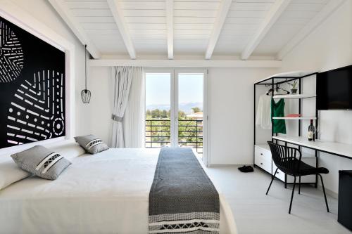 a white bedroom with a large bed and a desk at Cara a Bentu - Charming Rooms in Tortolì