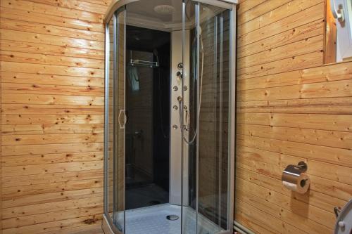 a glass shower in a bathroom with wooden walls at Breb Casa Luca in Breb