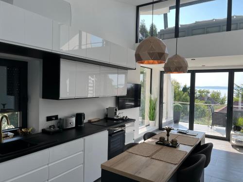 a kitchen with white cabinets and a wooden table at ARIS Apartman in Balatonvilágos