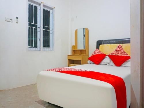 a bedroom with a bed with red and white pillows at OYO 91375 Pondok Feby Makassar in Makassar