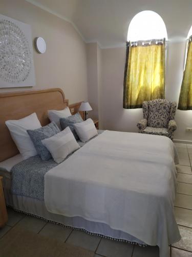a bedroom with a large white bed and a chair at For your best holiday in Rocas del Mar with amazing ocean view in Costa Del Silencio