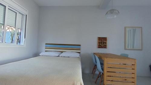 a bedroom with a bed and a wooden desk at Pousada Caminho Nômade in Garopaba