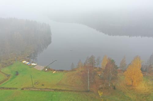 a misty hill with a group of houses in a field at Sjöutsikt, Röd trästuga med traditionellt yttre Skandinavisk, modernt inre och alla bekvämligheter, Sol hela dagen på stora altanen, Tryggt, Vinterbonat, Fiske, Båt in Skinnskatteberg