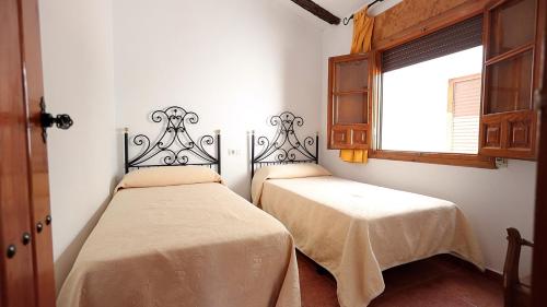 2 camas en una habitación con ventana en Aparthotel El Cañuelo, en Monturque