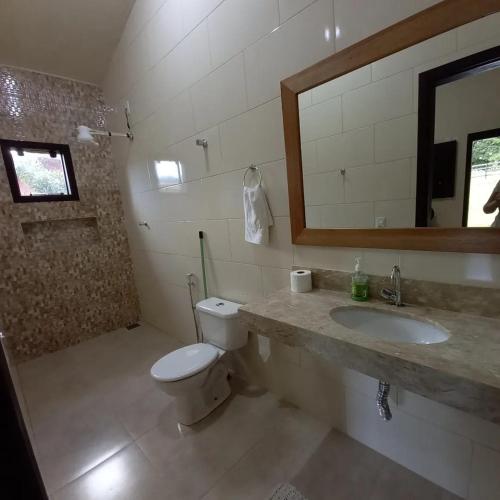 a bathroom with a toilet and a sink and a mirror at Pousada Recanto do Sossego- Serra da Canastra in Vargem Bonita