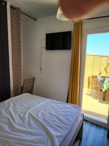 um quarto com uma cama, uma televisão e uma varanda em ESCALE OCEAN A 800 m DE LA PLAGE em Notre-Dame-de-Monts