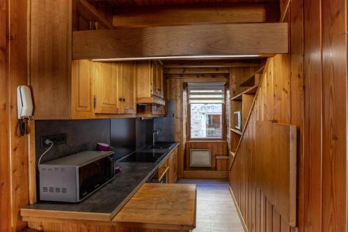 cocina con armarios de madera y microondas en La Cabane du Petit Tour en Langogne