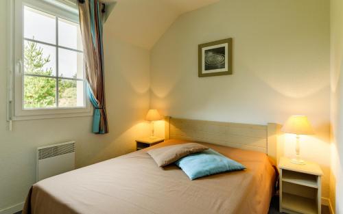 a bedroom with a bed with two lamps and a window at Lagrange Vacances Le Hameau De Peemor Pen in Crozon