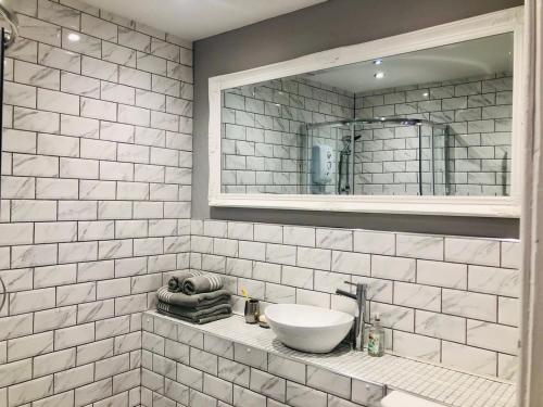 a white tiled bathroom with a sink and a mirror at Charming 1-Bed City Centre Apartment in Edinburgh in Edinburgh