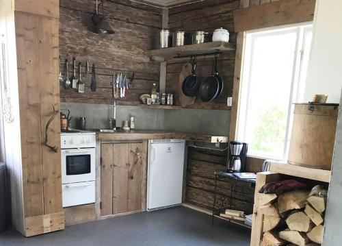a kitchen with white appliances and wooden walls at Cozy Stuga - Mountain View in Ramsele