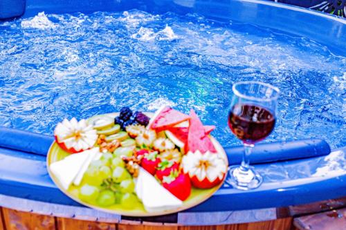 a plate of fruit and a glass of wine in a pool at PENSIUNEA MIHAELA-Transalpina in Novaci