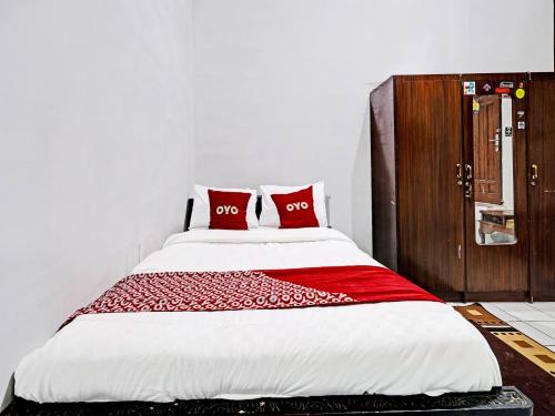 LebakwangiにあるOYO 91389 Anggrek Residence Syariahのベッド1台(上に赤い枕2つ付)