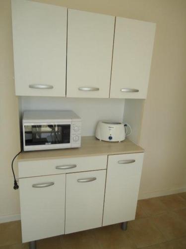 a kitchen with white cabinets and a microwave on a counter at Casa Patrick in Murcia