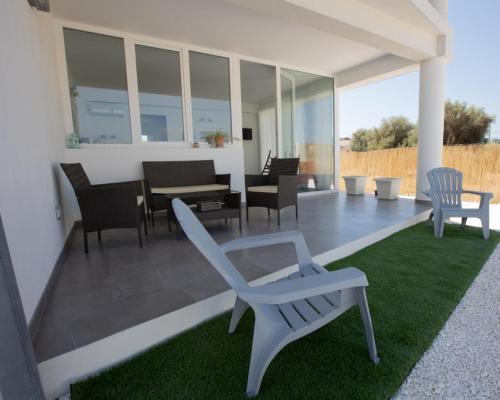 a patio with chairs and a table and a couch at White house in Avola