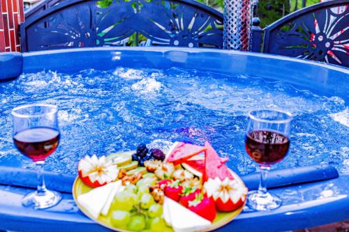 two glasses of wine and a plate of food in a hot tub at PENSIUNEA MIHAELA-Transalpina in Novaci